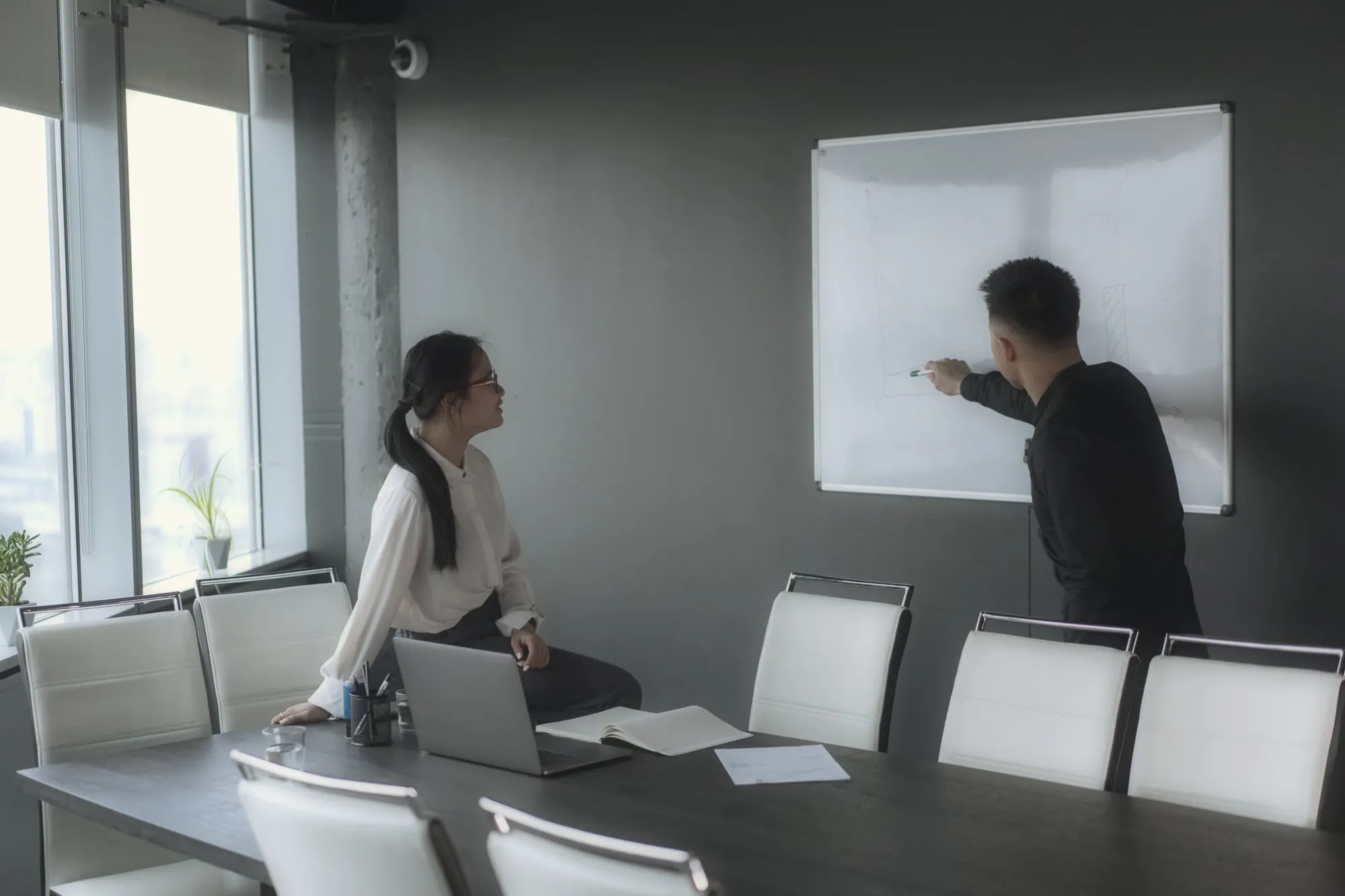 Two colleagues working through a plan at a whiteboard in a meeting room