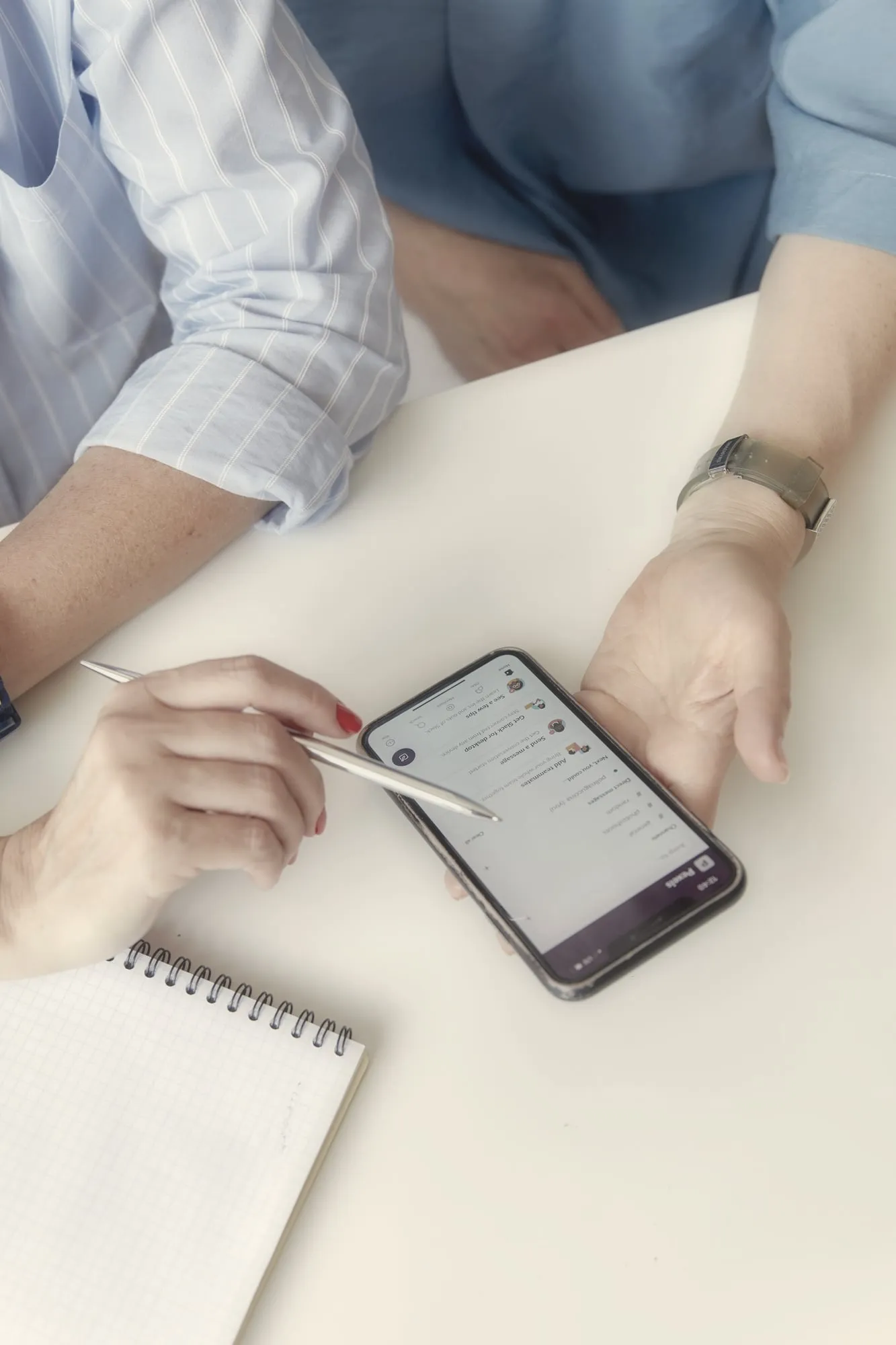 A phone on the table next to a pen and a notepad during a conversation
